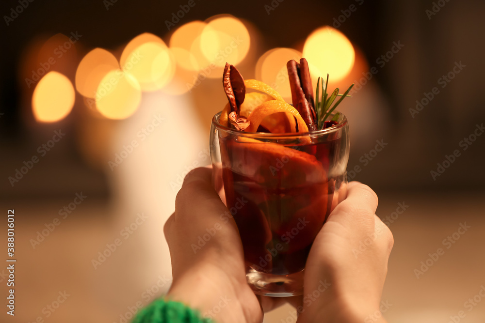 Woman drinking mulled wine at home in evening, closeup