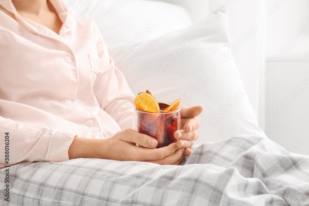 Woman with mulled wine in bedroom