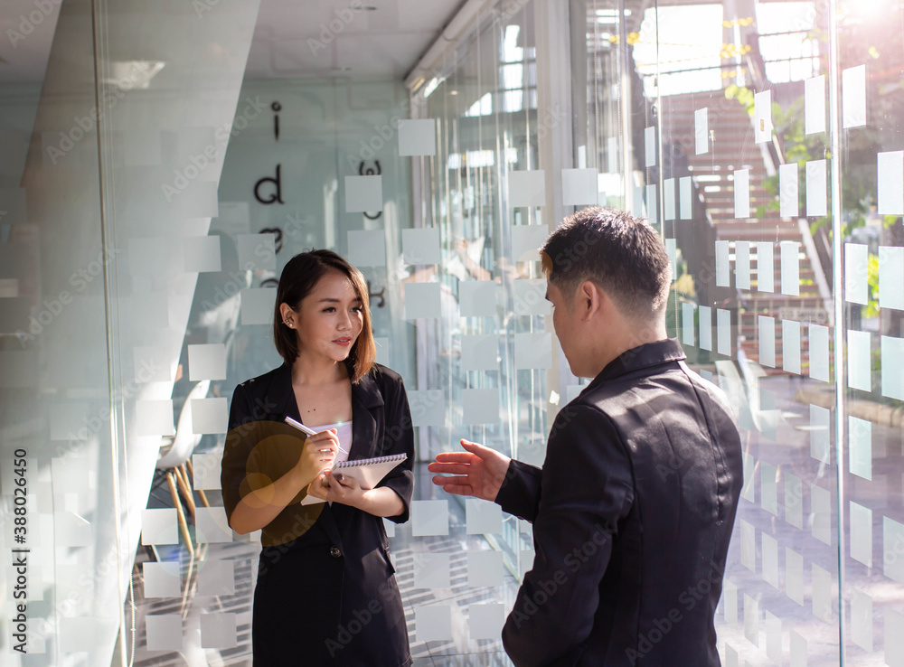 A young Asian woman takes notes of advice from business owners about the companys future travel pla