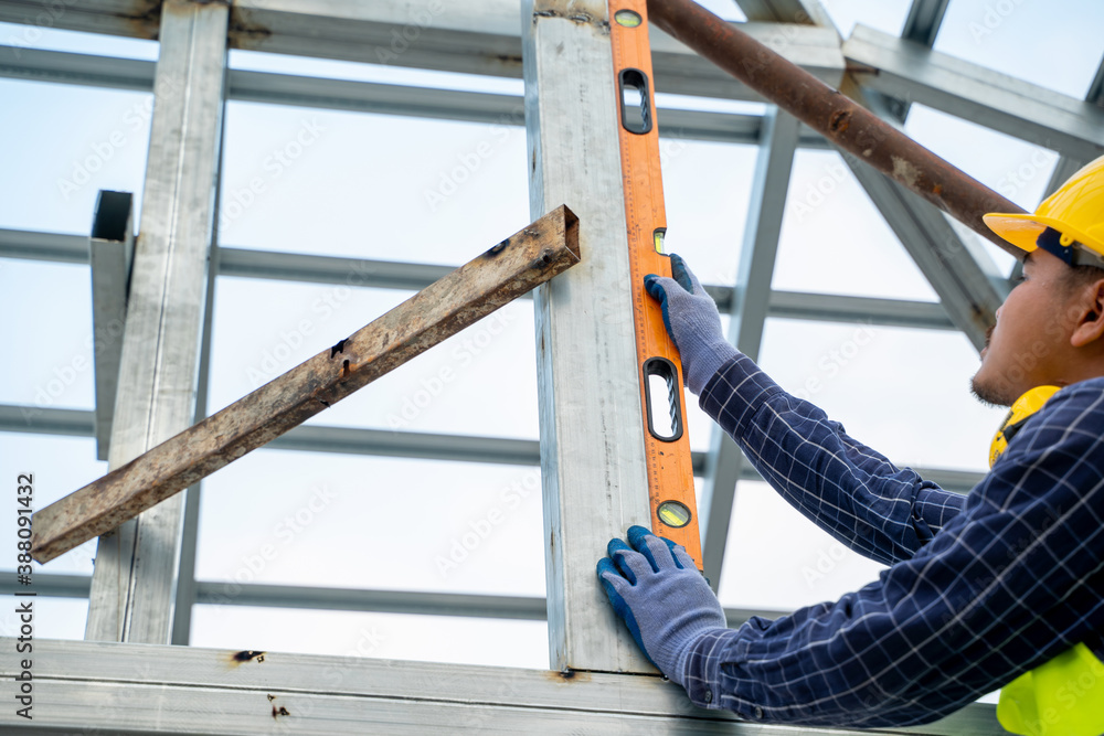 Construction worker measures level wall at window In the house under construction,Level is used to i