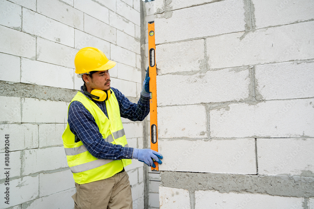 Construction worker measures level wall at window In the house under construction,Level is used to i