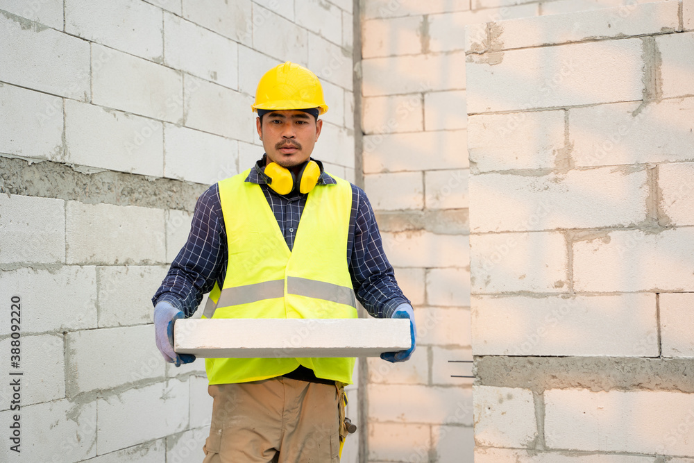 Masonry worker make concrete wall by cement block and plaster in the new house under construction.