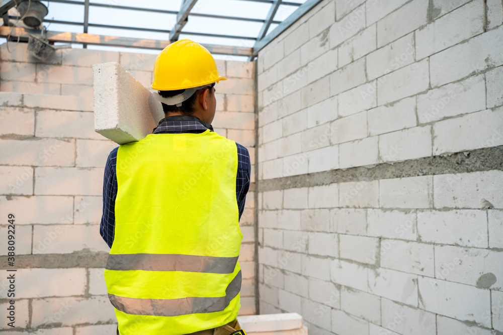 Masonry worker make concrete wall by cement block and plaster in the new house under construction.