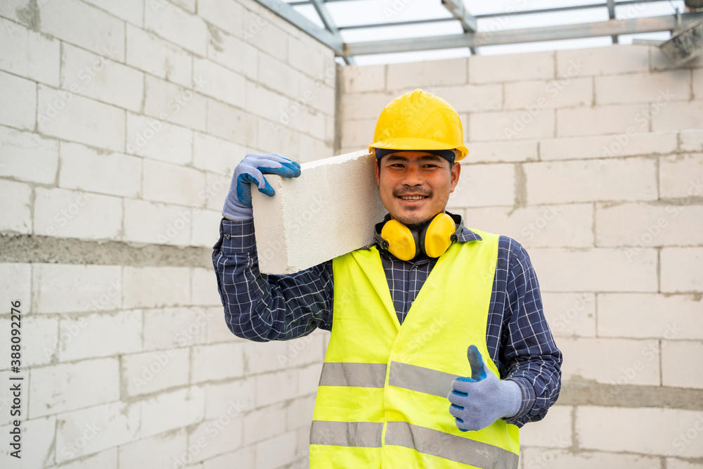 Masonry worker make concrete wall by cement block and plaster in the new house under construction.