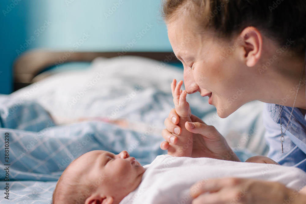 A young mom is kissing a newborn. Motherhood is the happiness of motherhood. New life of the infant 