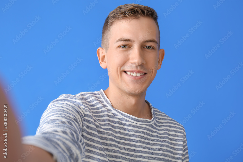 Young man taking selfie on color background