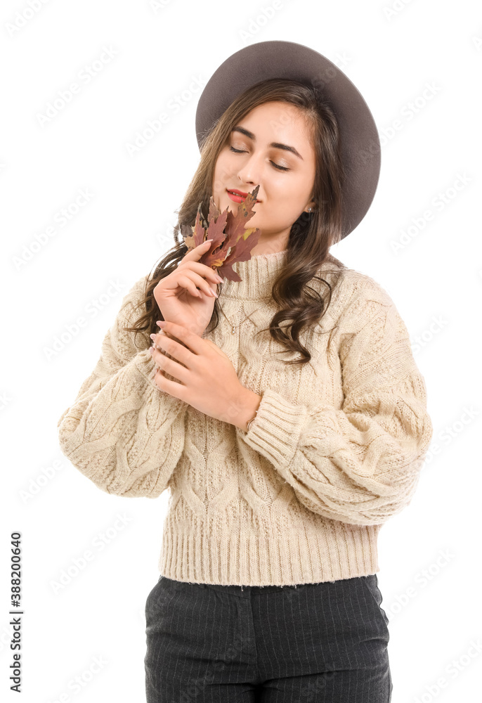 Stylish young woman with autumn leaves on white background