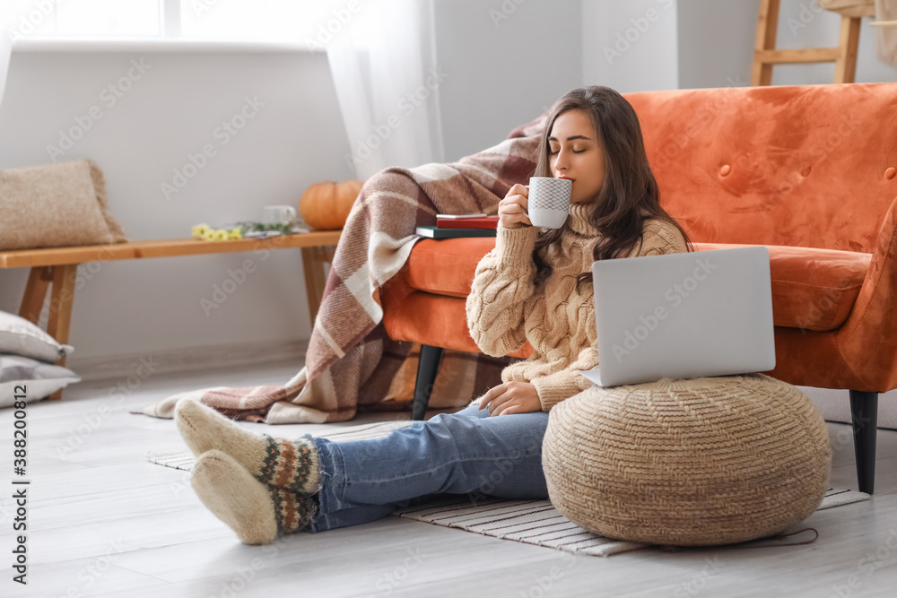 家里有笔记本电脑和一杯茶的漂亮年轻女人