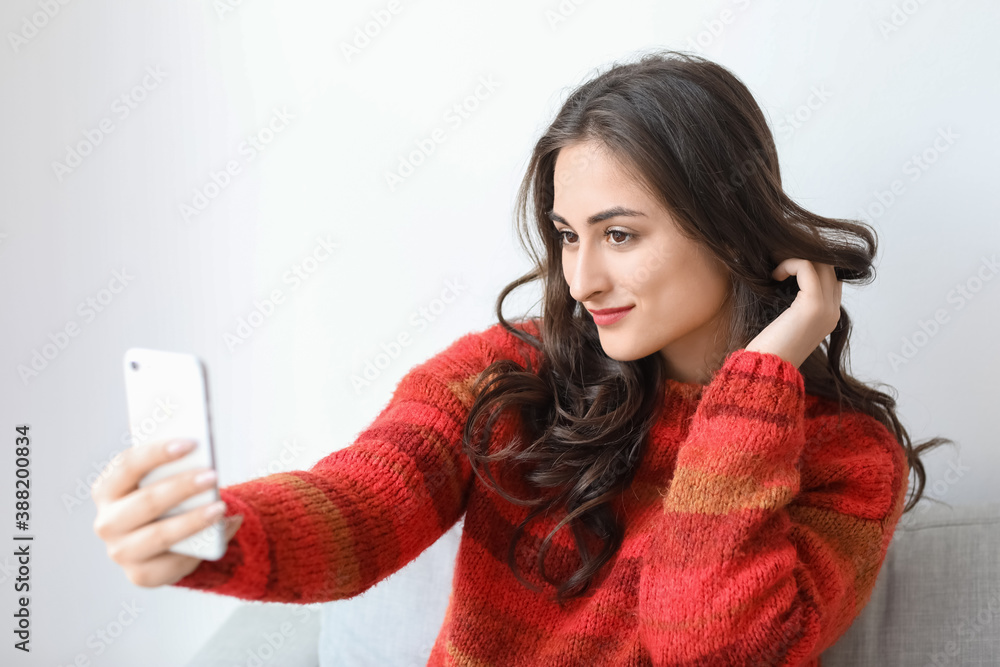 Beautiful young woman taking selfie at home