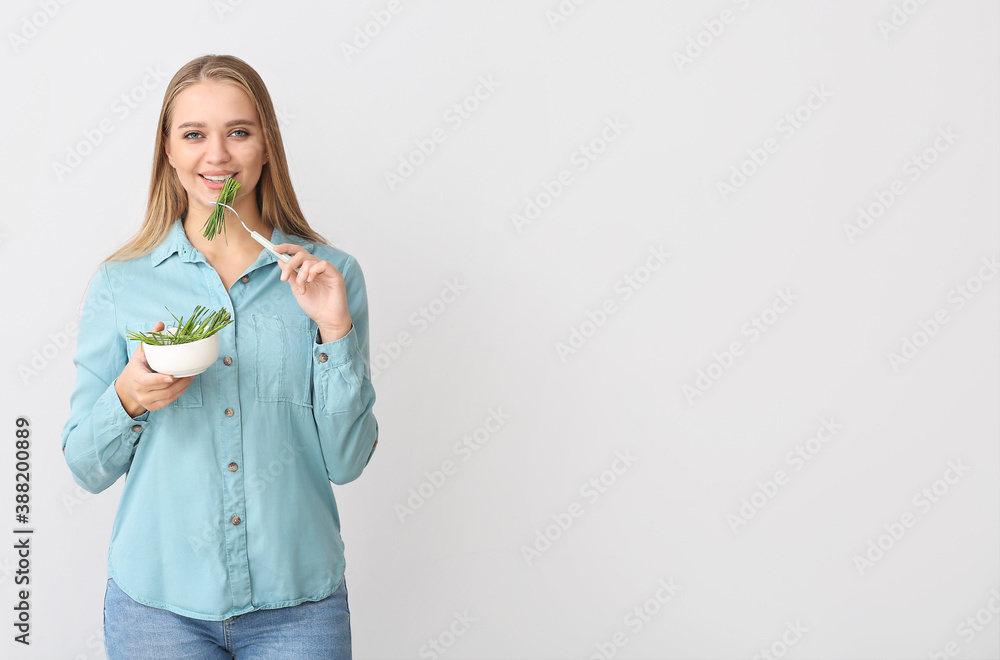 Young woman with wheatgrass on light background