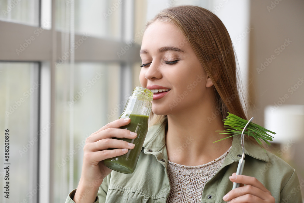 Young woman drinking wheatgrass juice at home