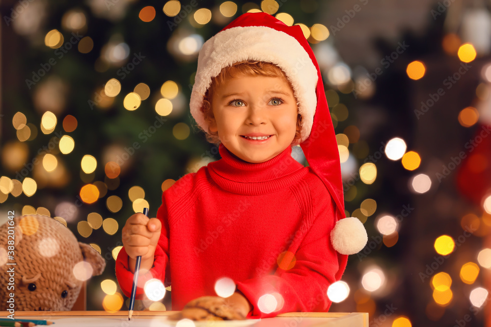 Cute little child writing letter to Santa at home