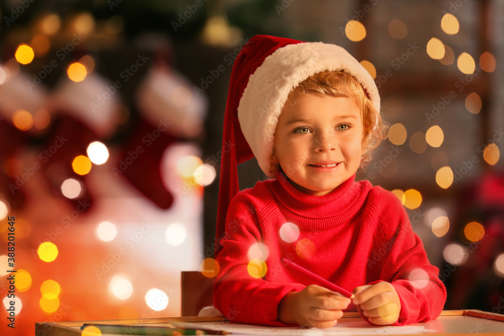 Cute little child writing letter to Santa at home