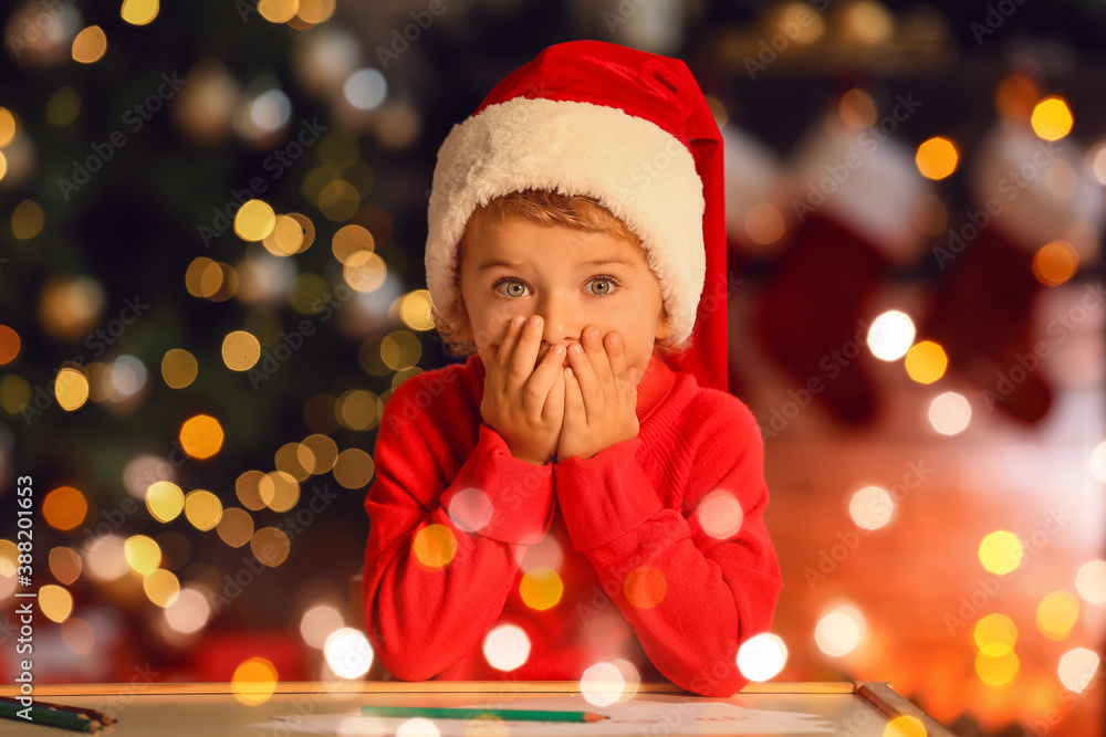 Cute little child writing letter to Santa at home