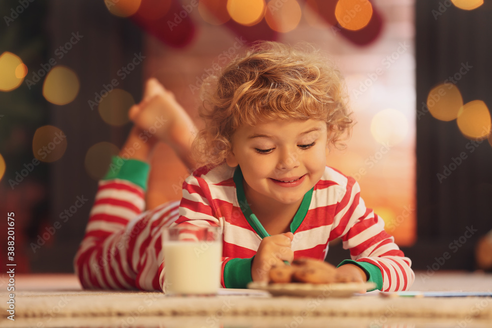 Cute little child writing letter to Santa at home