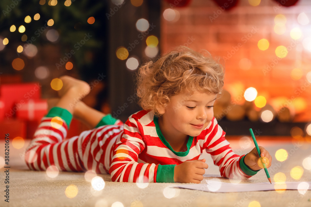 Cute little child writing letter to Santa at home