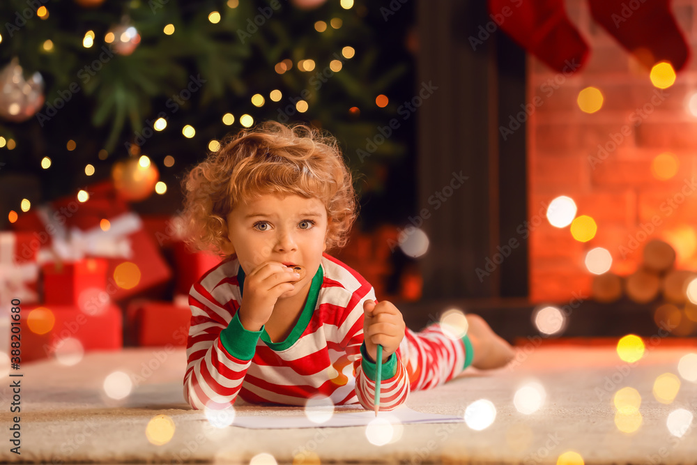 Cute little child writing letter to Santa at home