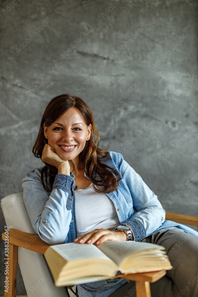 Brunette woman, casually dressed, sitting at home.