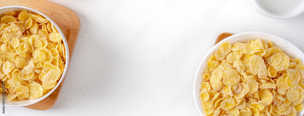 Top view of corn flakes bowl with milk on white background.