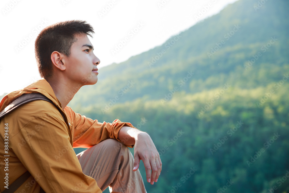 Asian teenager sitting on cliff bridge edge and looking at the mountain.