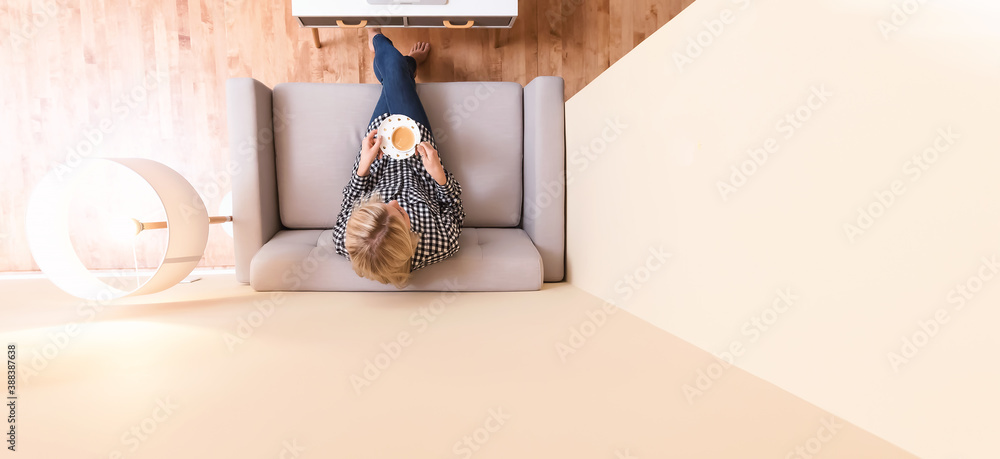 Young woman drinking a cup of coffee on a couch