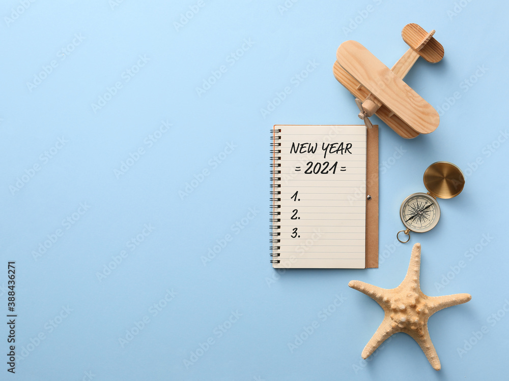 Notebook with empty to-do list for 2021 year and travel accessories on color background