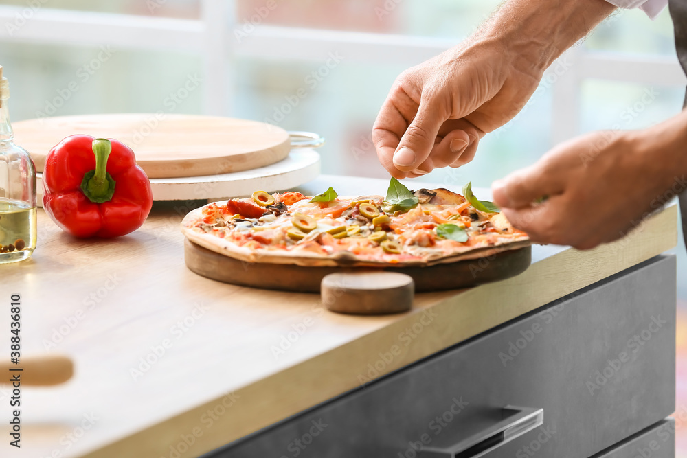 Mature male chef cooking tasty pizza in kitchen, closeup