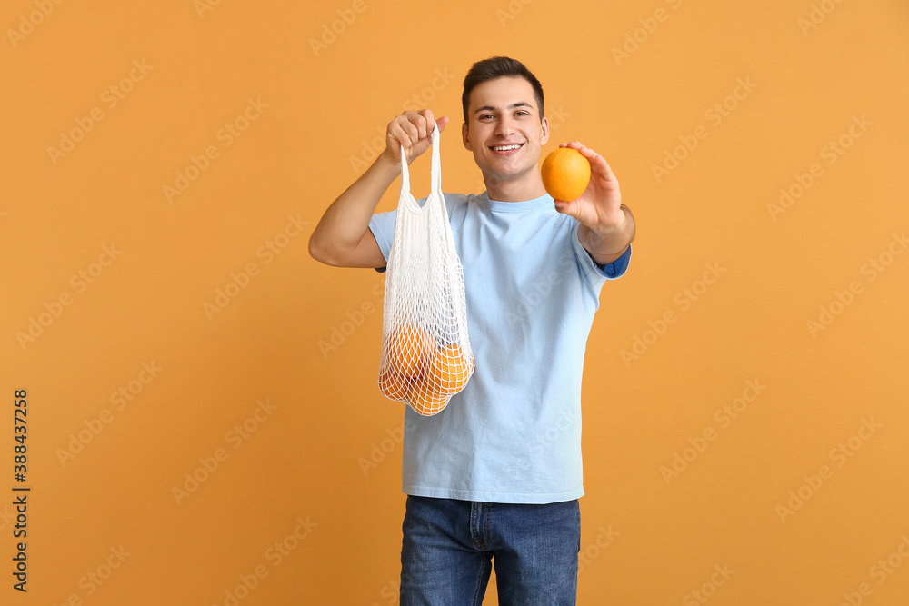 Handsome man with ripe oranges on color background