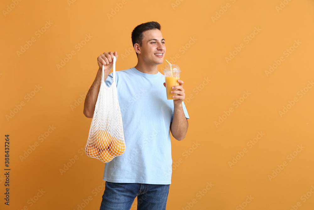 Handsome man with ripe oranges and juice on color background