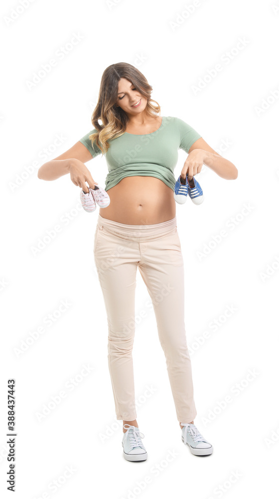 Beautiful pregnant woman with baby shoes on white background