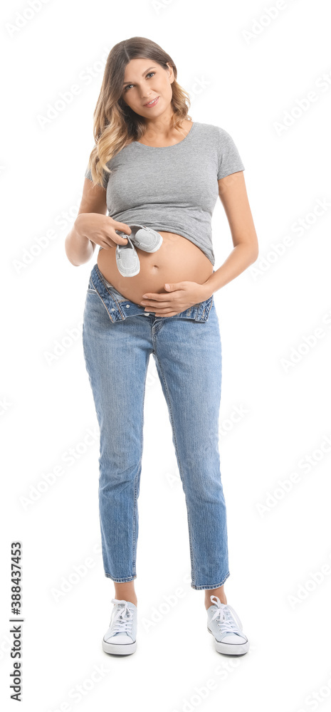 Beautiful pregnant woman with baby shoes on white background