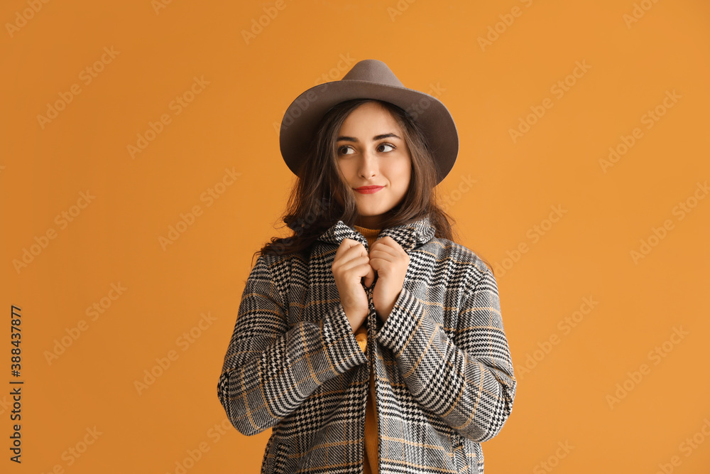 Stylish young woman in autumn clothes on color background