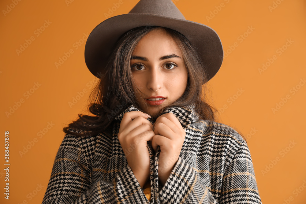 Stylish young woman in autumn clothes on color background