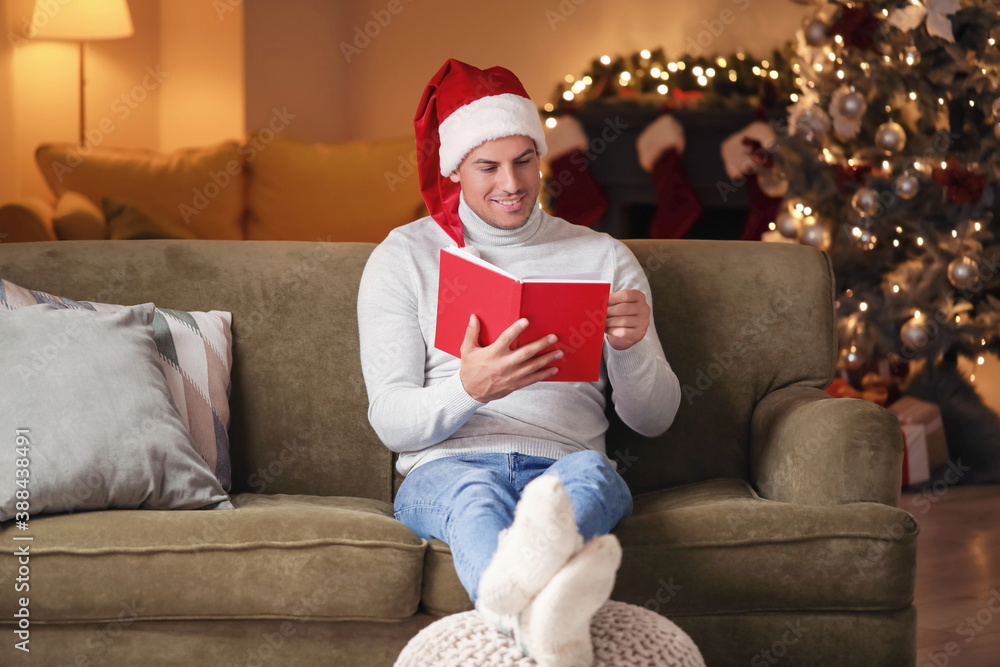 Handsome young man reading book at home on Christmas eve