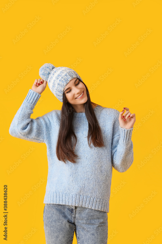 Beautiful young woman in winter clothes on color background