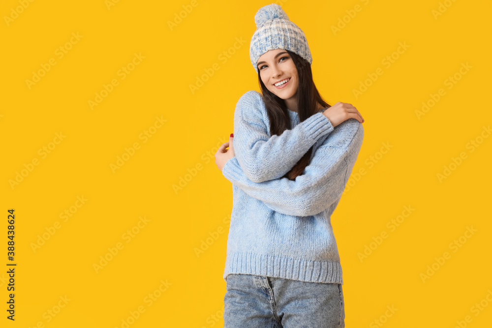 Beautiful young woman in winter clothes on color background