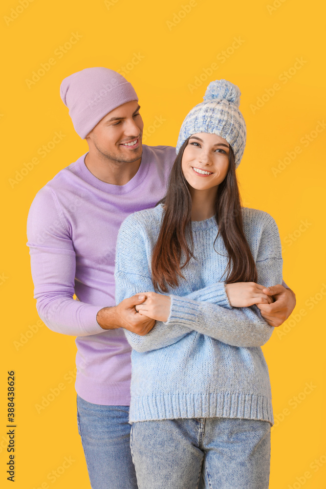 Young couple in winter clothes on color background