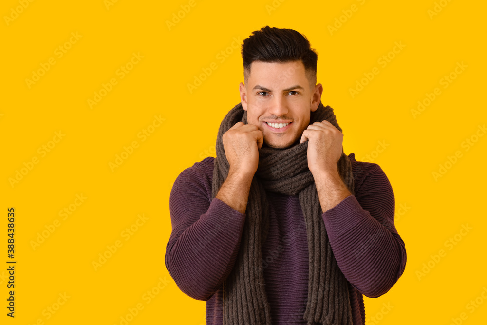 Handsome young man in winter clothes on color background