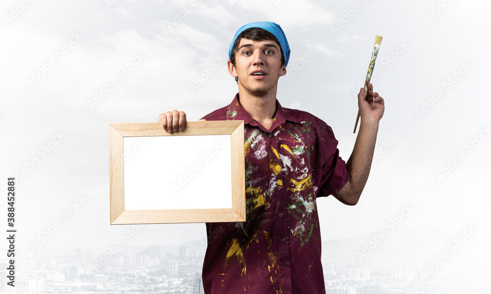 Young handsome painter artist holding paintbrush