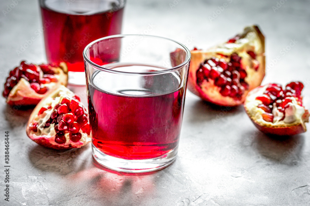 fresh pomegranate with juice in glasses on kitchen background