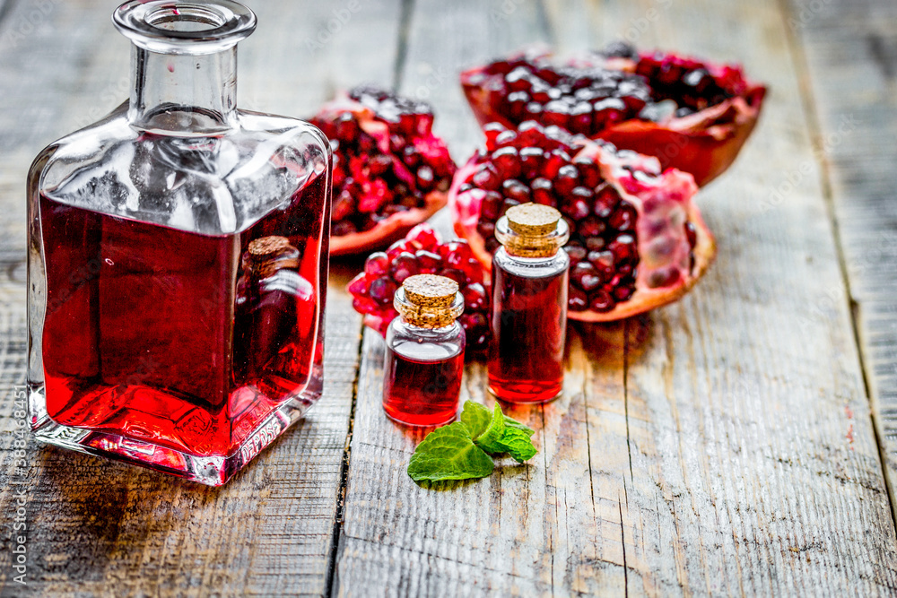 sliced pomegranate and extract in glass on wooden background