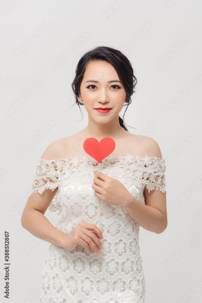 Elegant Asian woman holding a parper heart and standing isolated over white background.