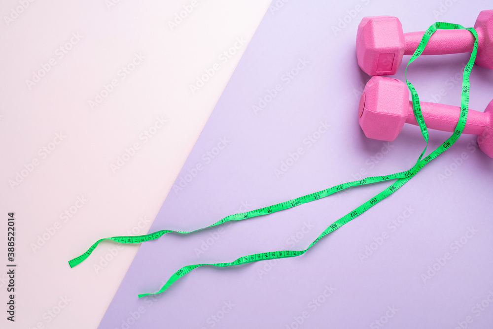 Pink fitness dumbbells and slimming tape