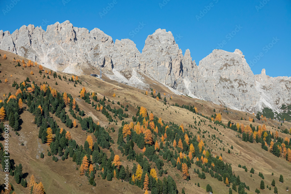 AERIAL Dolomites tower over valley filled with steep pastures and colorful trees