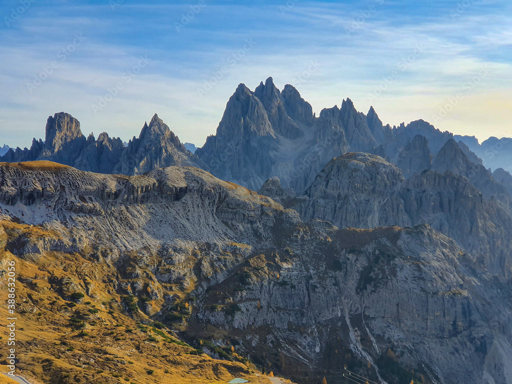 DRONE: Flying over a grassy valley and toward the rocky mountain range in Alps.