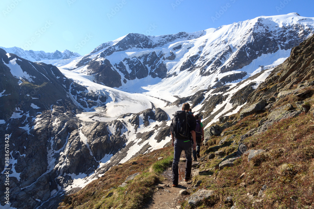 Group of people hiking towards glacier Taschachferner and mountain snow panorama with blue sky in Ty