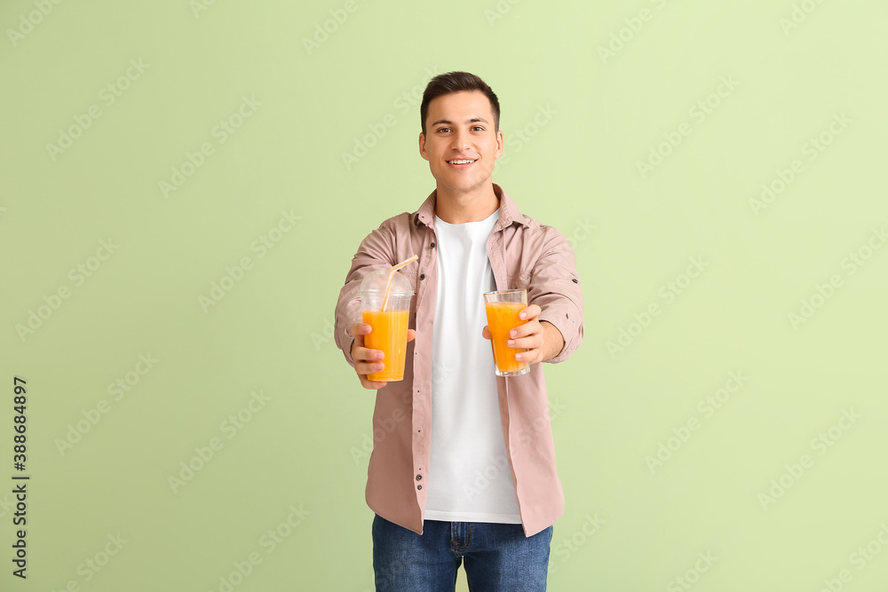 Handsome man with orange juice on color background