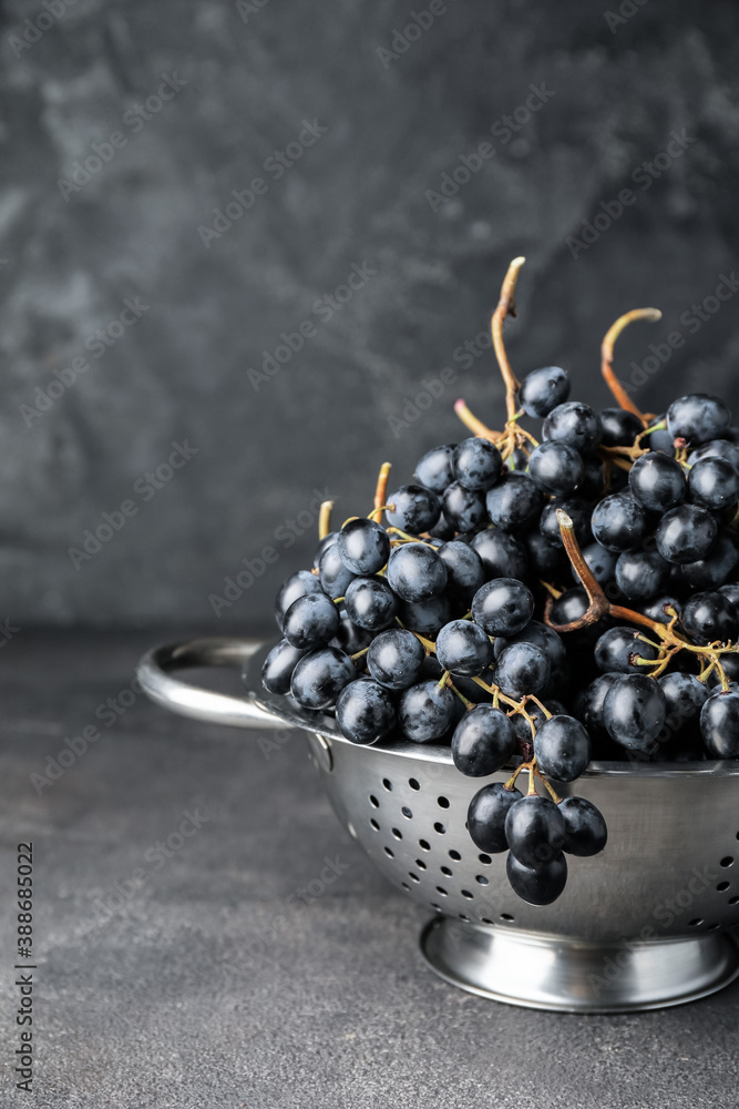 Sweet ripe grapes in colander on table