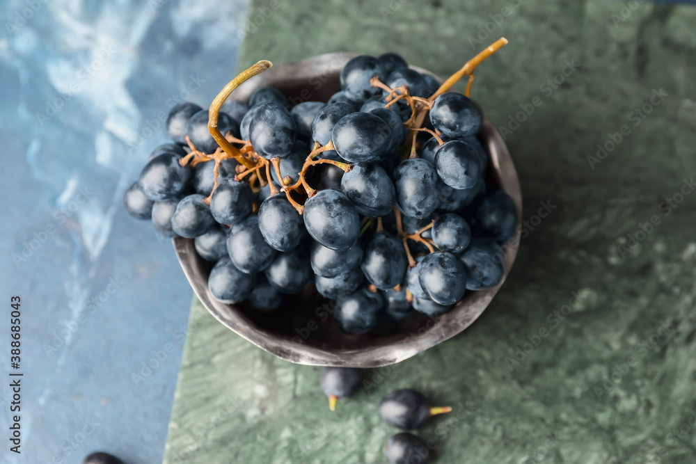 Colander with sweet ripe grapes on table