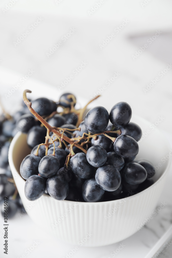 Bowl with sweet ripe grapes on table